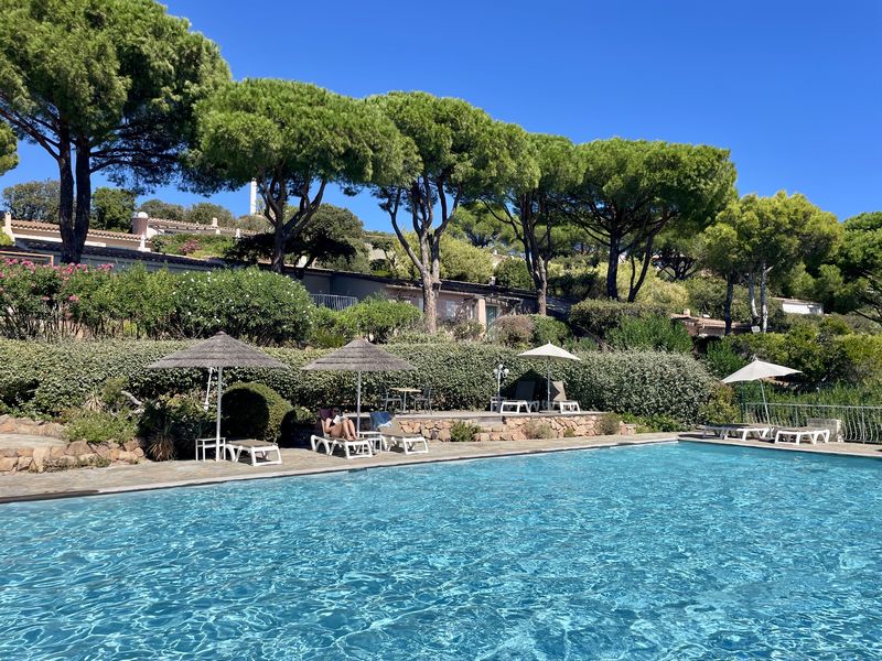 La grande piscine chauffée de la résidence, entourée de pins parasols et de transats