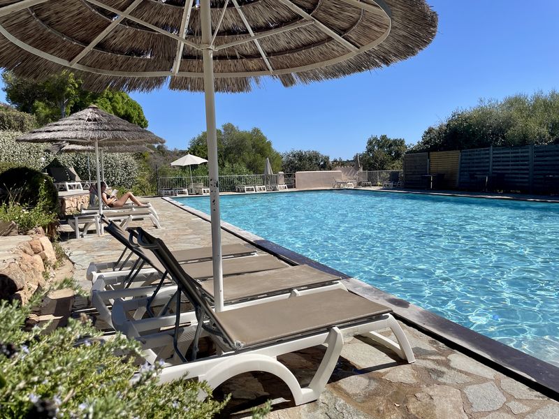 Transats sous les parasols en paille au bord de la piscine